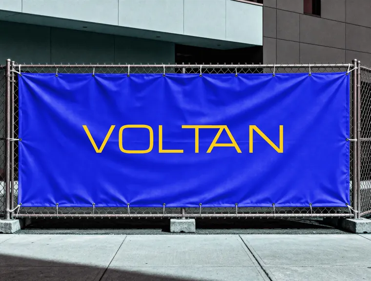 VOLTAN-Schriftzug in Gelb auf einem blauen Bauzaun-Banner vor einem Gebäude